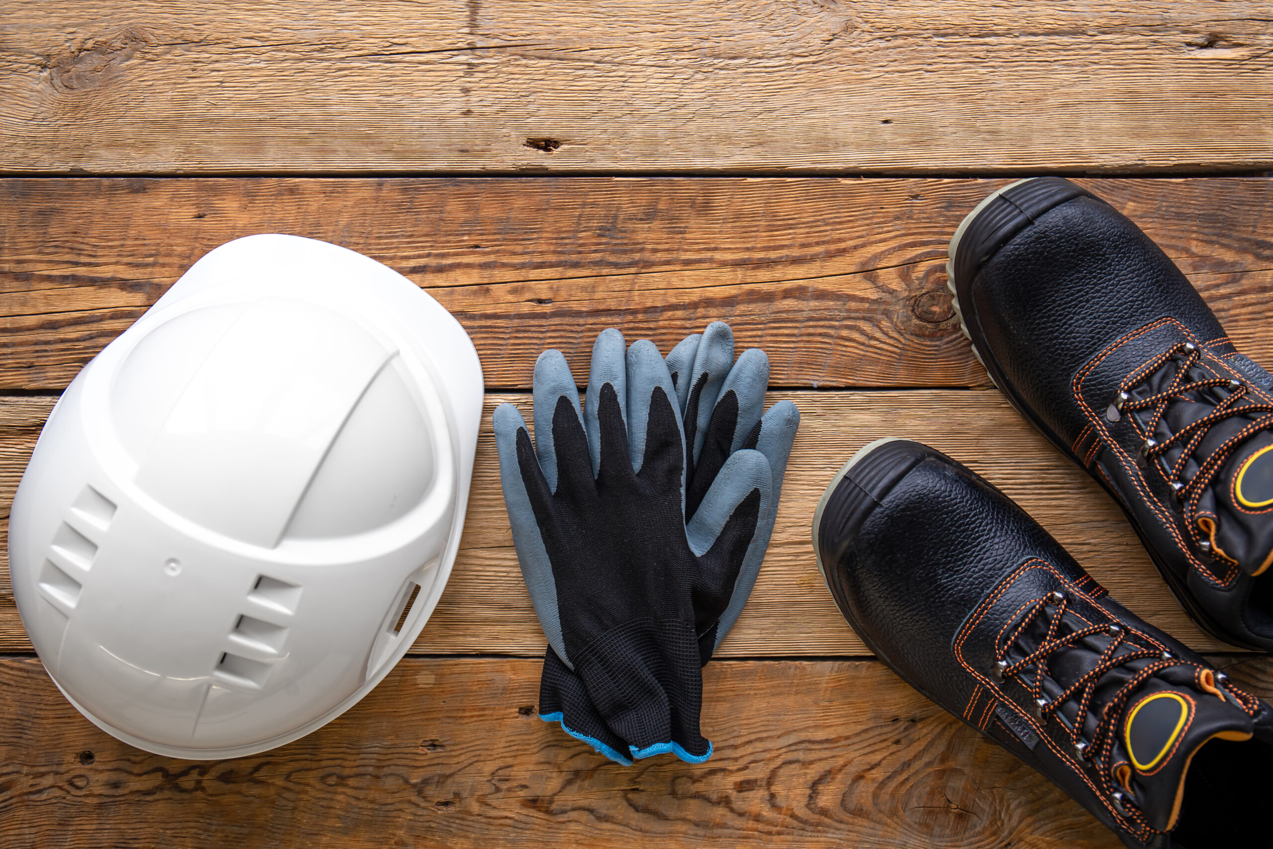 work helmet, boots and gloves on a wooden background, top view.